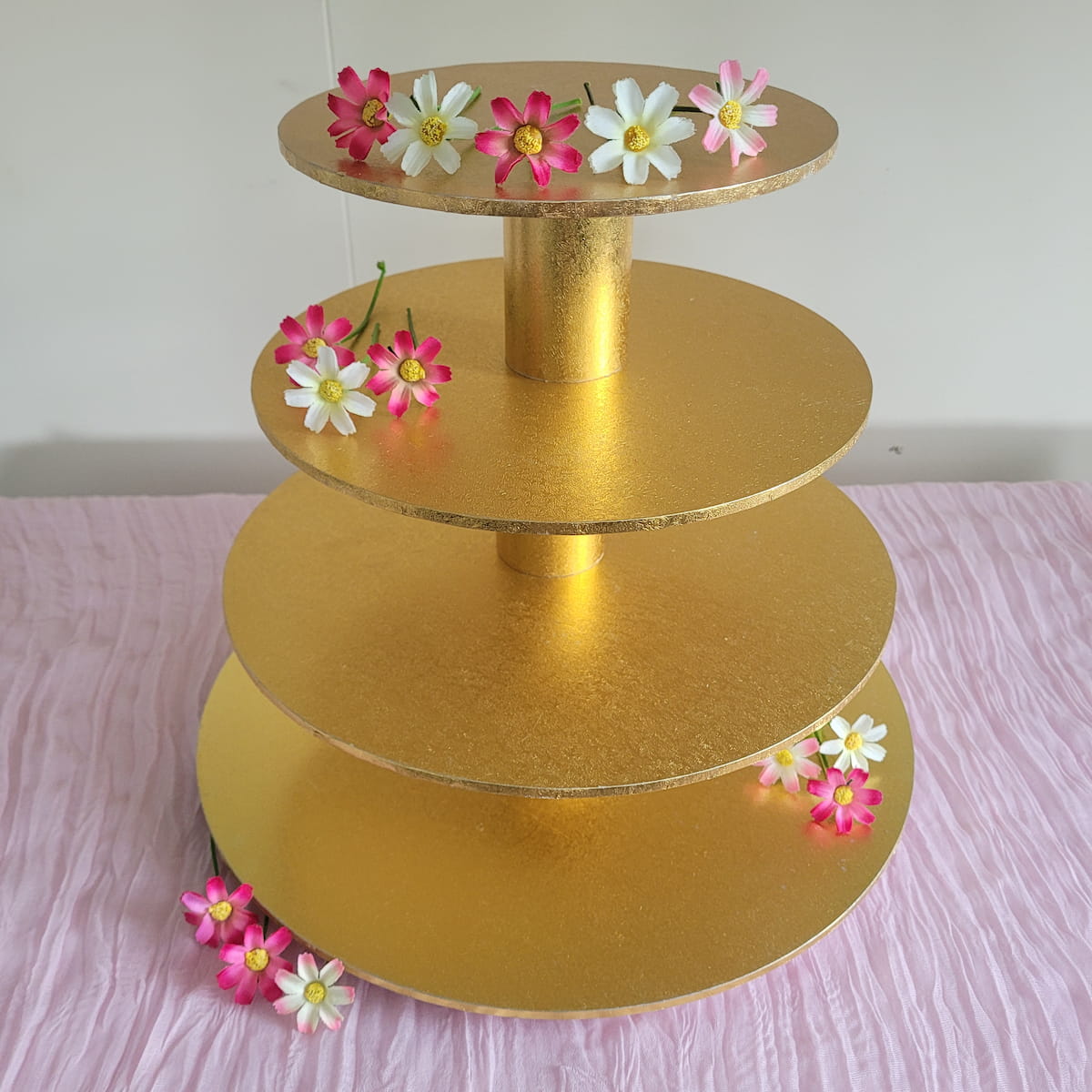 4 tier gold cupcake stand with daisy flowers on pink cheesecloth