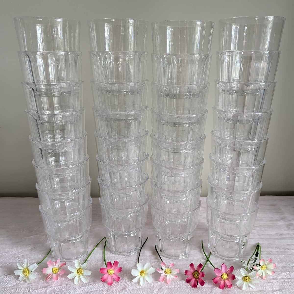 32 small acrylic tumblers stacked in four columns with daisies