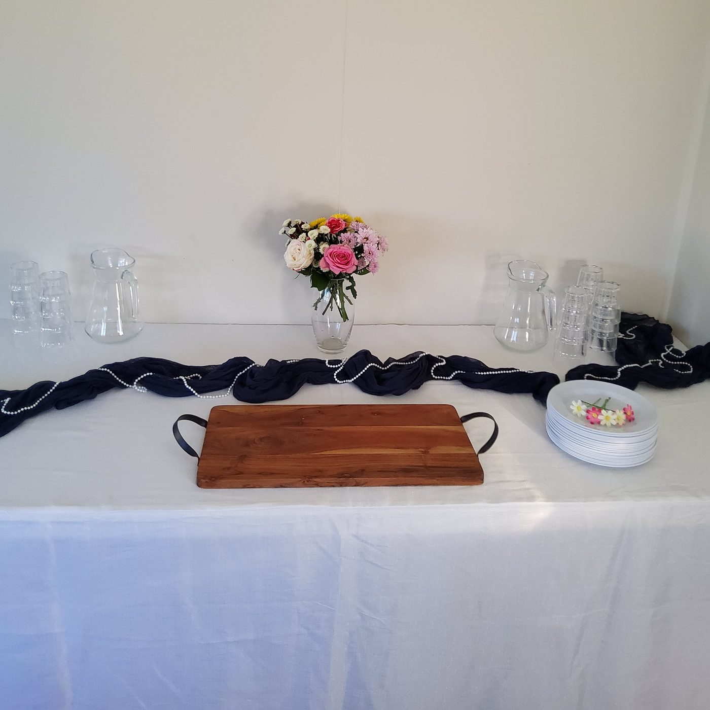Party table with navy cheesecloth runner and pearl garland on white cloth