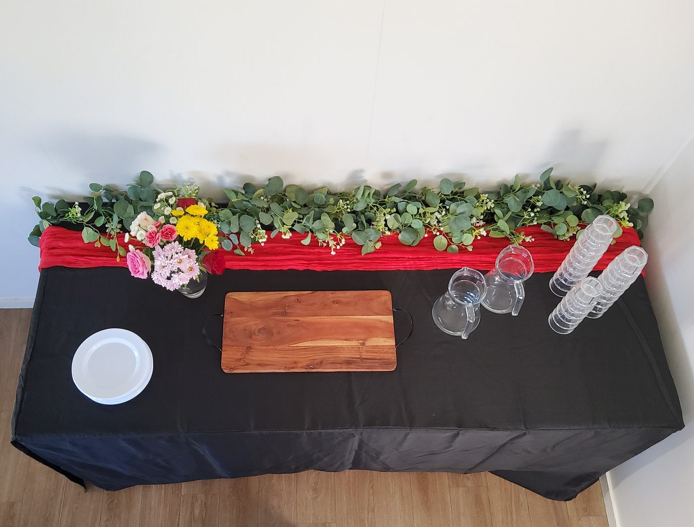 Party table with red cheesecloth runner and eucalyptus garland