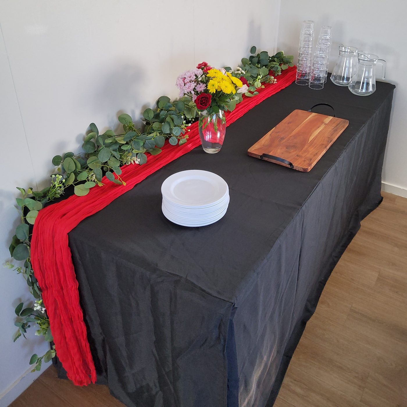 Styled party table with red runner and floral garland