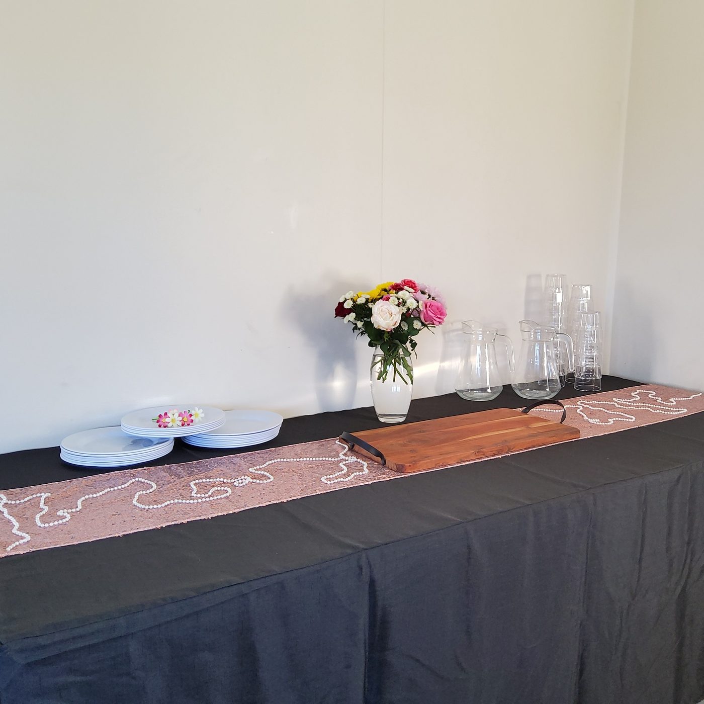 Party table with rose gold sequin runner and pearl garland on black cloth