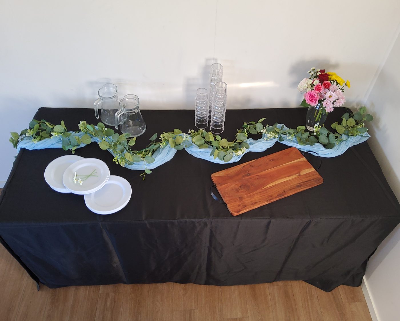 Party table with sky blue runner and eucalyptus garland on black cloth