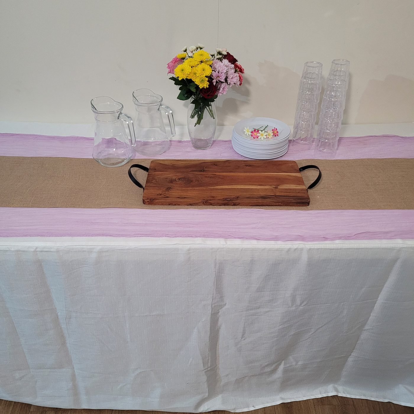 Party table with pink cheesecloth runner over hessian