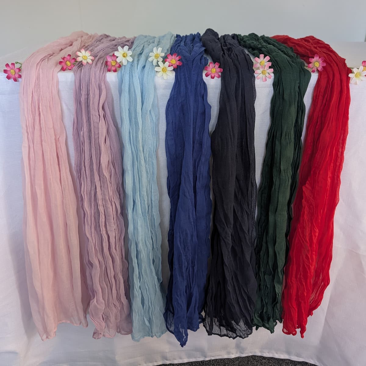Cheesecloth table runners in 7 colours hanging with daisies