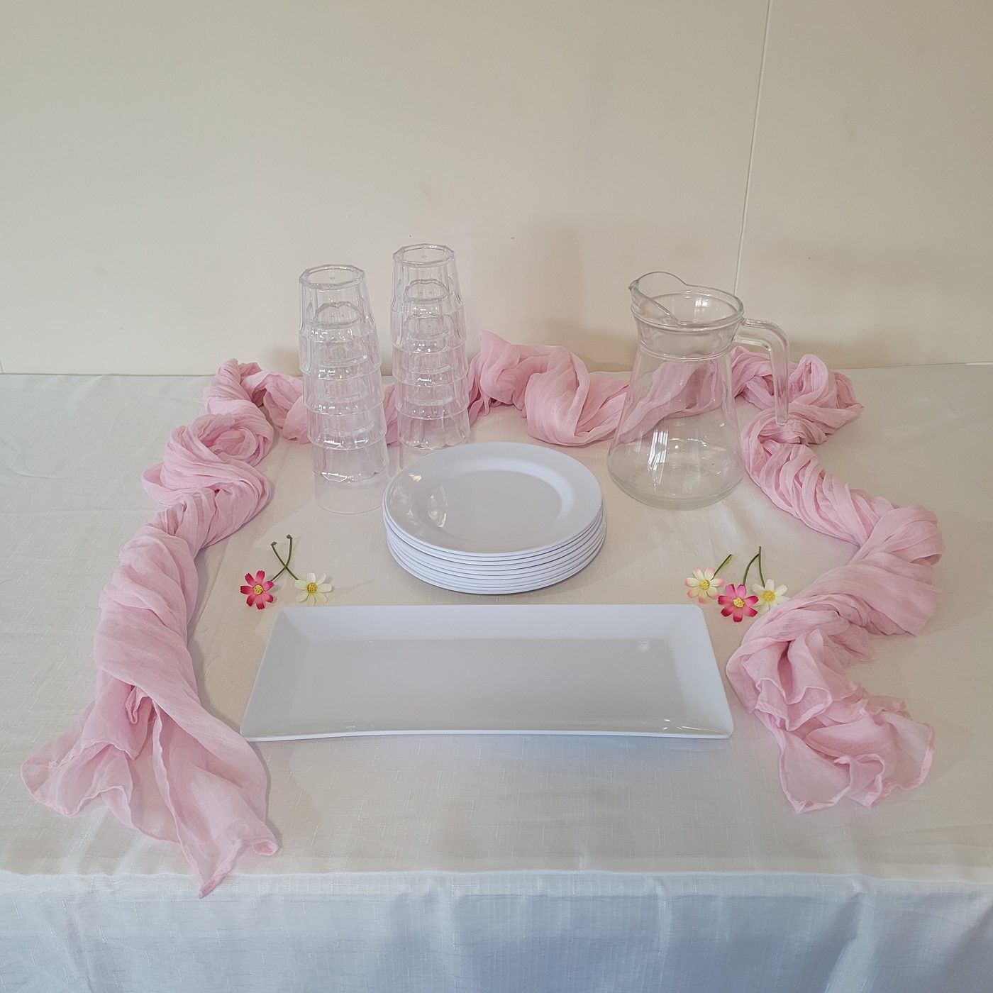 Starter setup with pink cheesecloth runner, plates, tumblers and platter